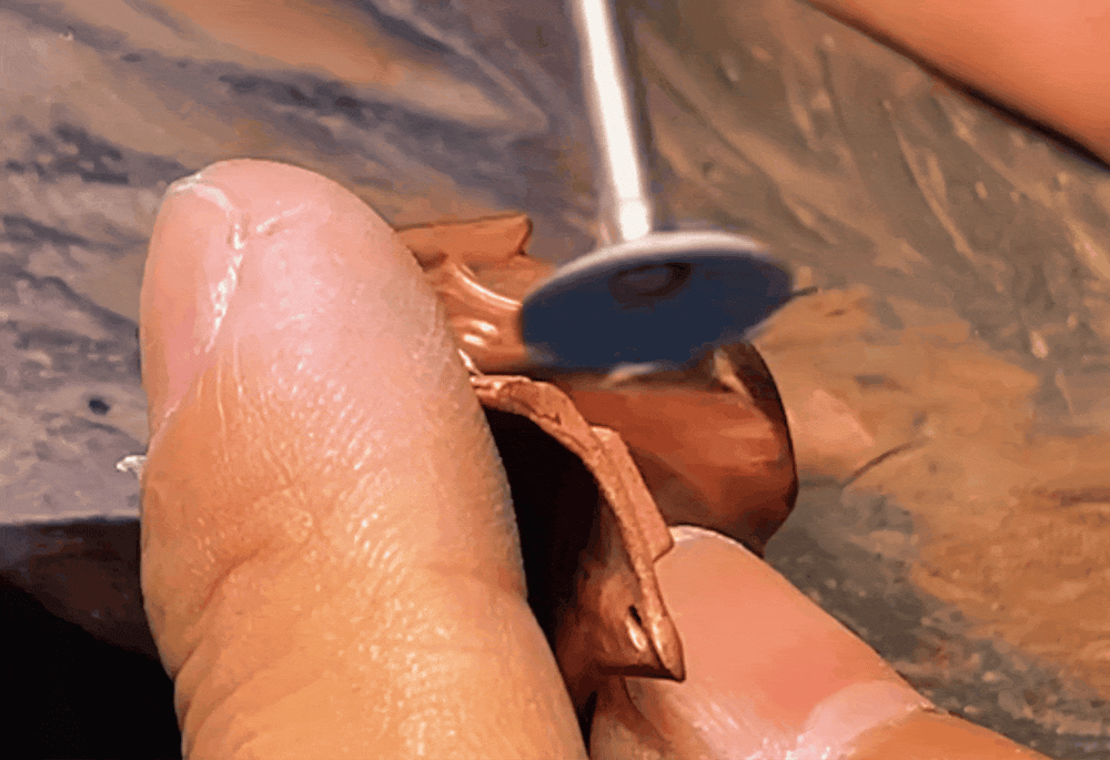 A rotary tool polishing a small metal piece
